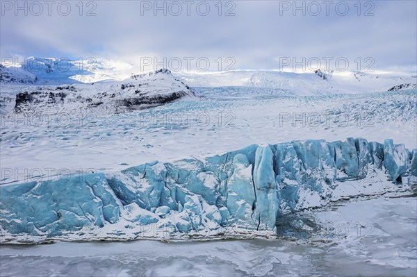 Snow-covered icebergs in the Fjallsarlon glacier lagoon, with the Öraefajökull glacier behind,