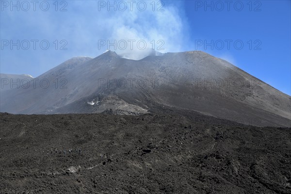 Hiking group below the smoking crater of the volcano Etna, Province of Catania, Sicily, Italy,