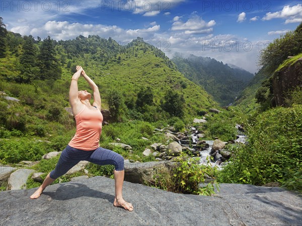 Yoga outdoors, sporty fit woman doing Ashtanga Vinyasa Yoga asana Virabhadrasana 1 Warrior pose