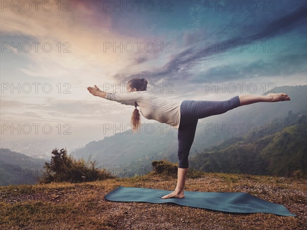 Yoga outdoors, sporty fit woman doing Ashtanga Vinyasa Yoga asana Virabhadrasana 3 Warrior pose