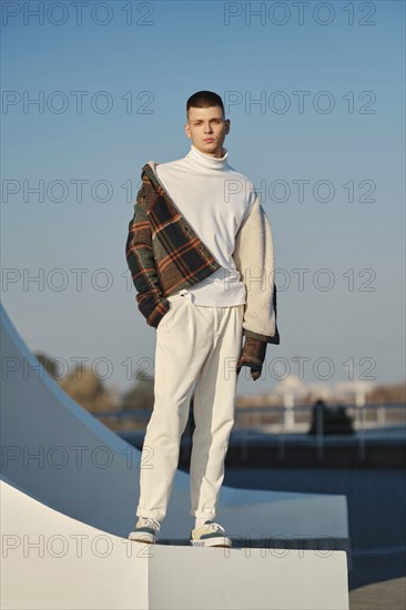 Urban fashion. Young man in loose clothes takes off on the street