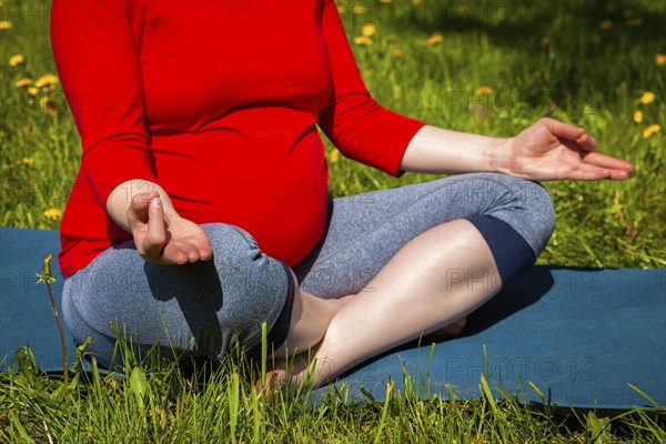 Pregnancy yoga exercise, pregnant woman doing asana Sukhasana easy yoga pose with chin mudra