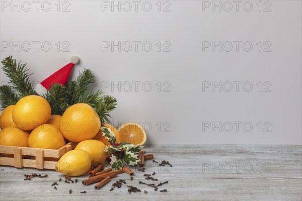 Wooden basket with oranges and lemons, cloves and cinnamon sticks, Christmassy, light background,