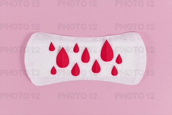 Female period concept with panty liner with symbolic paper blood drops on pink background