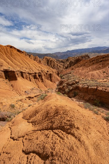 Eroded mountain landscape with sandstone cliffs, canyon with red and orange rock formations,