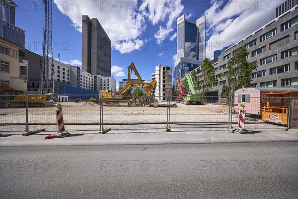 Construction site for the demolition of a building with construction fence and hydraulic excavators