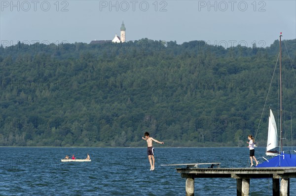 Boy and girl bathing in the lake, children jumping over diving board into the water, jetty of