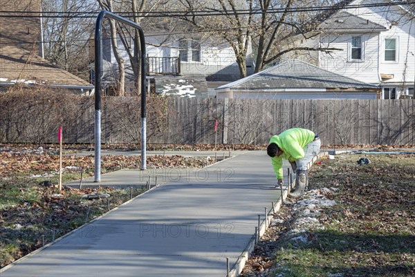 Detroit, Michigan - Workers pour and finish concrete for walking paths in Three Mile Park in