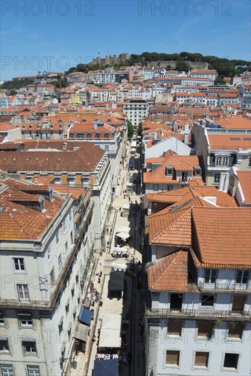 Aerial view of a narrow alley with tall buildings and red tiled roofs in a sunny city, view of