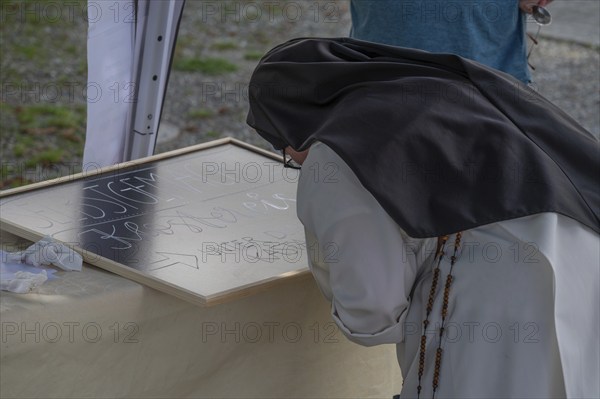 A nun from the Dominican Order writing an offering board at a monastery festival, Dominican nunnery