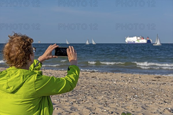 Older woman taking photos of boats, sailing boats, ferry, smartphone, Kieler Woche, Falckensteiner