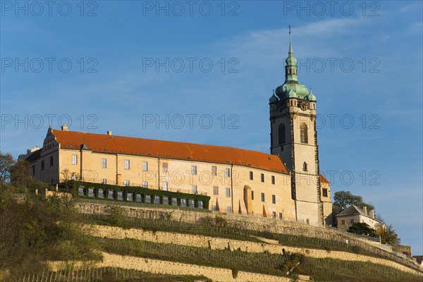 Historic castle with tower on a hill under a blue sky in the evening sun, Melnik Castle, Church of