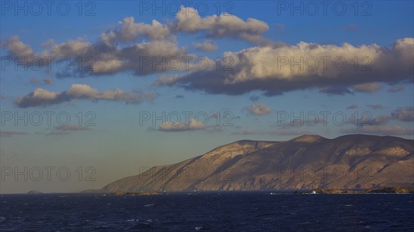 Vast seascape with mountains in the background and a sky full of clouds in daylight, Kassos Island,