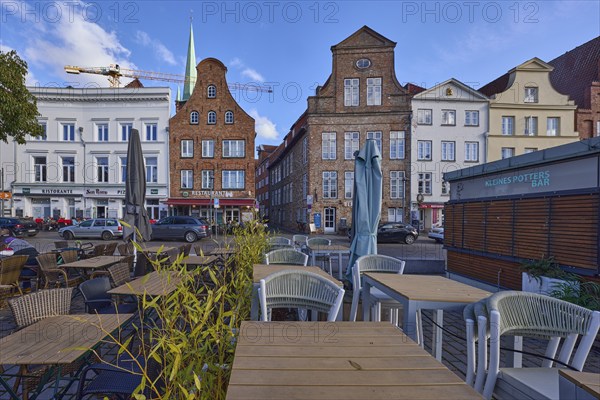 Outdoor area of a restaurant with tables, chairs and parasols, historical building, gable, street