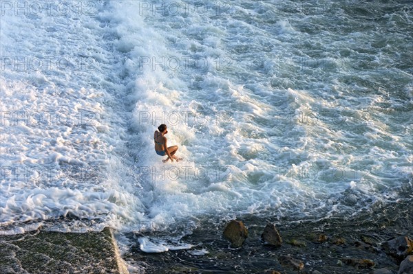 Girl bathing in the spray of the Lech weir, jumping into the white foaming water of the cascades,