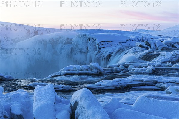 Icefall at the edge of the Godafoss waterfall at dawn, snow-covered landscape, Northern Iceland