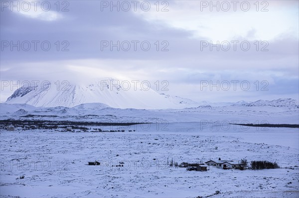 Snow-covered extinct volcano Hverfjall, lonely farmhouse in front, near Lake Myvatn, Northern
