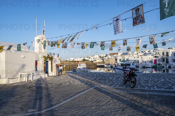 White Cycladic Greek Orthodox Church of Agios Nikolaos, decorated with flags, harbour of Naoussa,