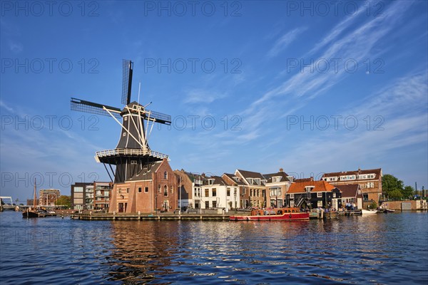 Harlem cityscape, landmark windmill De Adriaan on Spaarne river with boats. Harlem, Netherlands