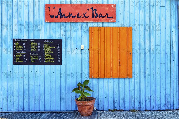 Colourful hut, wooden facade of a bar with orange closed shutter and menu, advertising alcoholic