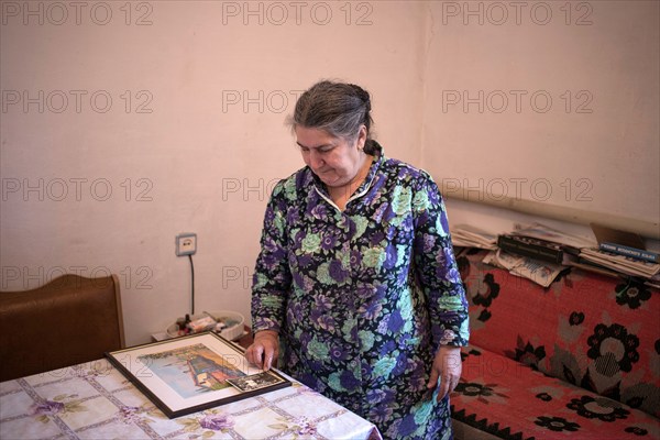 A Crimean Tatar woman in her home looks at a picture of her family's house in front of deportation