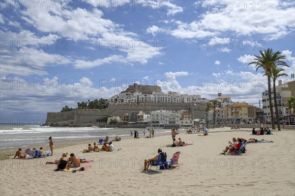 Tourists on the beach, in the background the old town with the Romanesque castle from the 14th