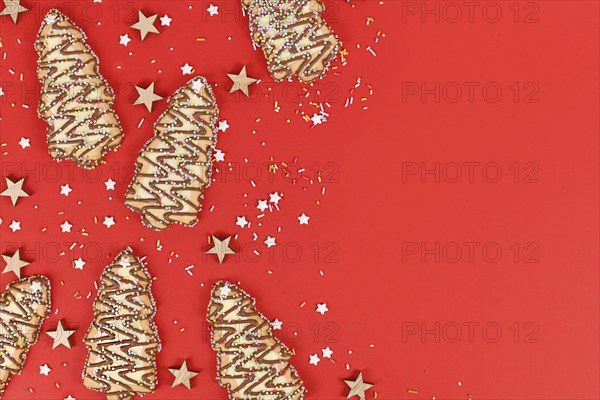 Christmas tree shaped cookies with sugar sprinkles on red background