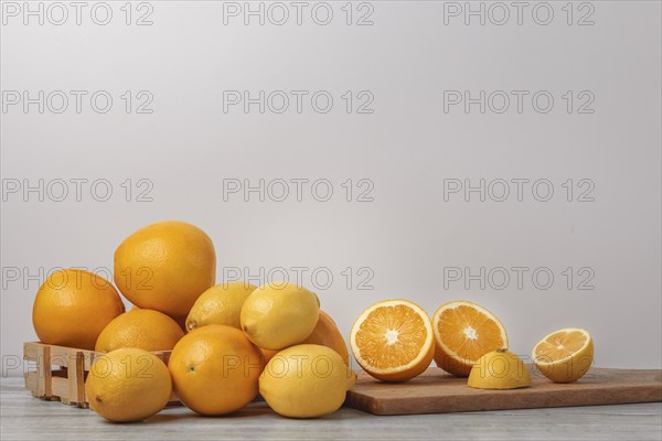 Basket and wooden board with oranges and lemons, vitamin C, light background, copy room
