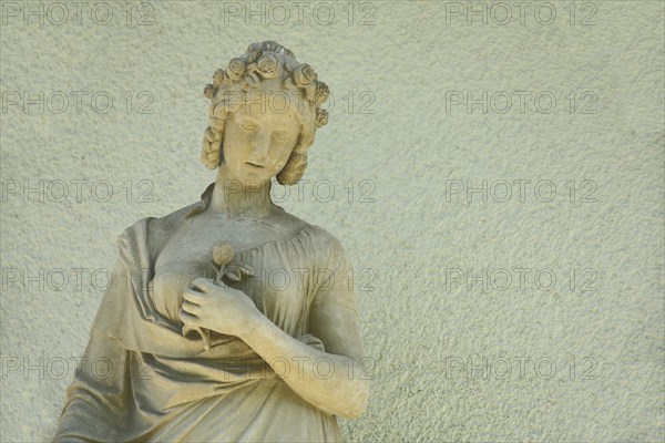 Sculpture of a woman with hair ornament and rose, flower in arm, holding hand, stone, yellow,