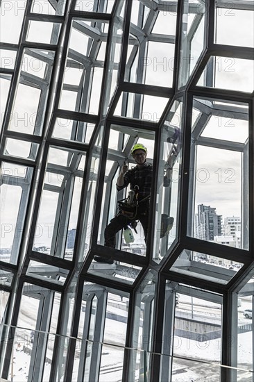 Window cleaners cleaning the glass facade of the Harpa Concert Hall and Congress Centre, interior