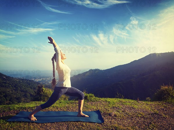 Yoga outdoors, sporty fit woman doing yoga asana Virabhadrasana 1, Warrior pose posture outdoors in