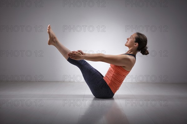 Beautiful sporty fit yogini woman practices yoga asana Paripurna navasana, boat pose