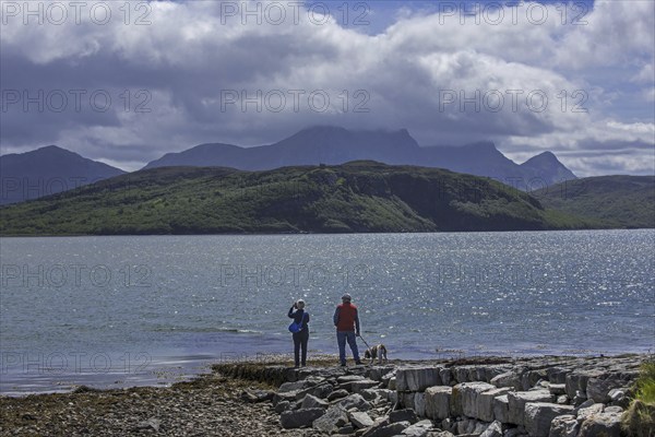 Tourists looking over Ben Loyal and Kyle of Tongue, shallow sea loch in northwest Highland,