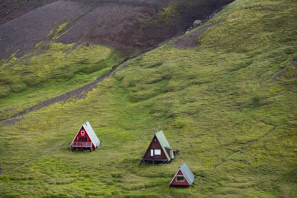 Cabins among volcanic landscape with black sand and green grass, Ásgarður, Kerlingarfjöll,