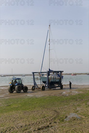 Tractor launching boat in cradle, River Blackwater estuary, West Mersea, Mersea Island, Essex,