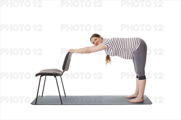 Pregnancy yoga exercise, pregnant woman doing yoga asana Uttanasana Standing Forward Fold Pose with