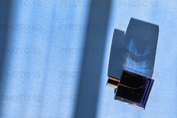 Bottle of perfume for men on blue background under sun light from the window