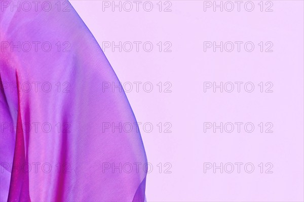 Pink tulle netting fabric with blue hue on side of pink background with copy space