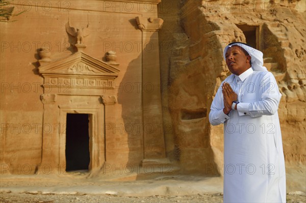 Rawi, storyteller, in front of the Nabataean tombs at the rock Qasr Al-Bint, Hegra or Madain Salih,