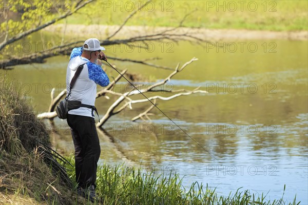 Fisherman trying to do a perfect cast, throwing lure. Spining fishing, angling, catching fish.