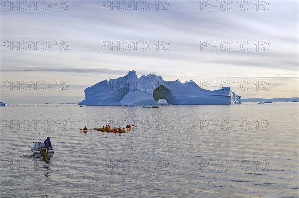 Small boat and kayaker in front of iceberg with large ice cave, Ilulissat, Disko Bay, Denmark,