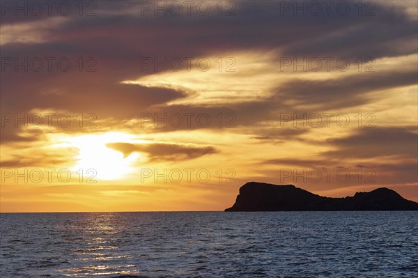 Black rocky coast orange hillem, grey clouds, sunset, dusk, Marettimo, Egadi Islands, Sicily,
