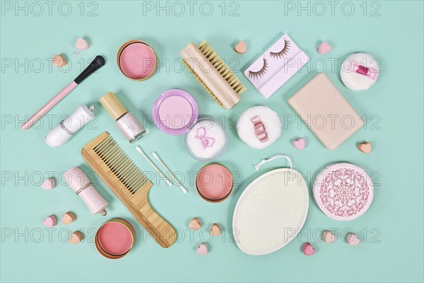 Pink makeup beauty products like brushes, powder or lipstick on teal blue background