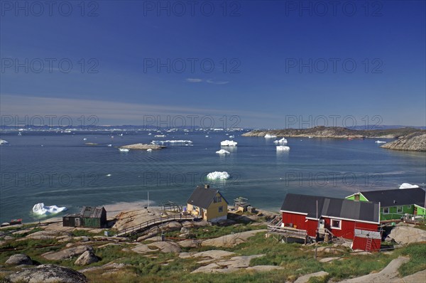 Simple, colourful houses on the edge of a bay covered with icebergs, Ilulissat, Arctic, Disko Bay,