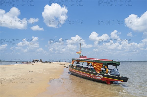 Wooden tourist boat, sightseeing boat beached on Braamspunt, sandbar on the Suriname River, where