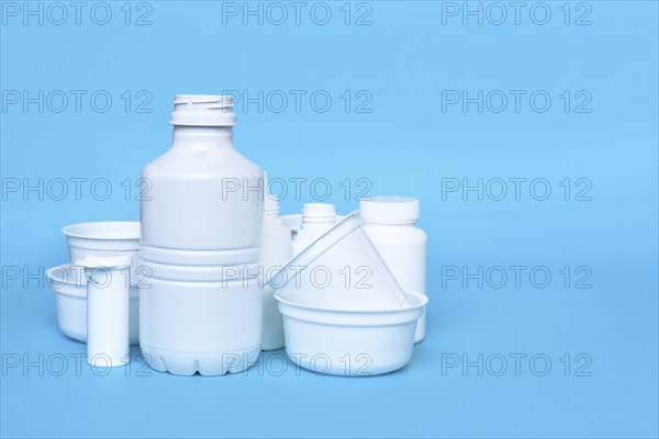 Different empty plastic waste packages on blue background with negative space