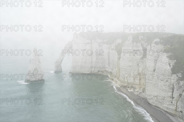 L'Aiguille and the Porte D'Aval, a natural arch in the chalk cliffs at Etretat in the mist, Côte