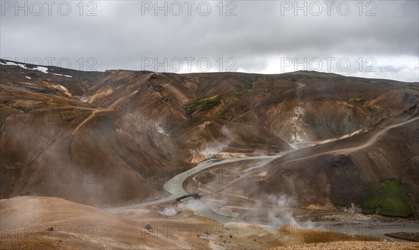 Bridge and steaming streams between colourful rhyolite mountains in the Hveradalir geothermal area,