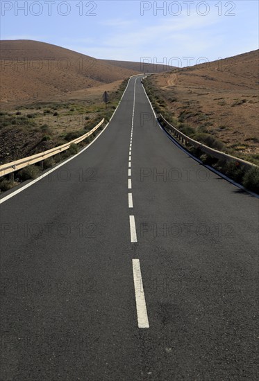 Tarmac road crossing barren desert mountainous land between Pajara and La Pared, Fuerteventura,