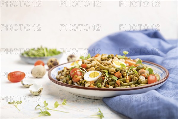 Mung bean porridge with quail eggs, tomatoes and microgreen sprouts on a white concrete background